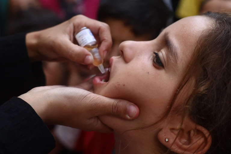 Une soignante administre le vaccin contre la polio par voie orale à une enfant