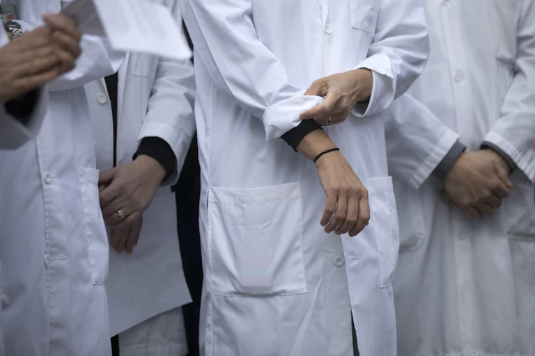 Close up of a doctor in white lab coat rolling up their sleeves