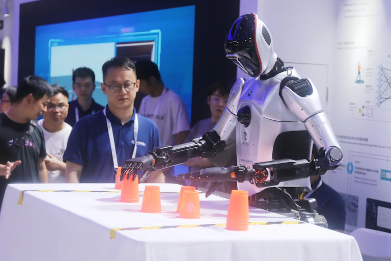 A robot has its hands on orange cups.