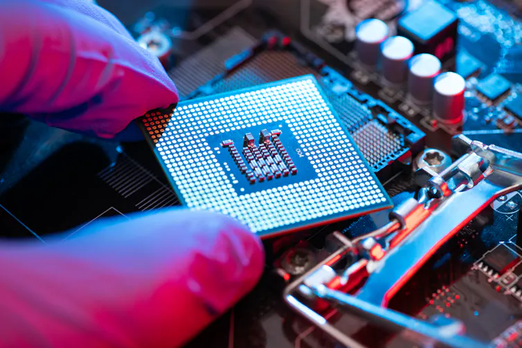 Close-up of gloved hand holding square semiconductor chip