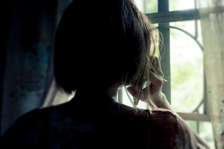 Woman silhouetted against window talking on the phone.