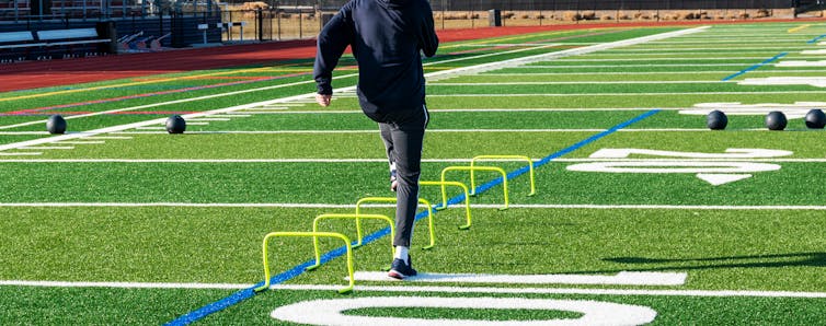 A runner skips over an obstacle course in a field.