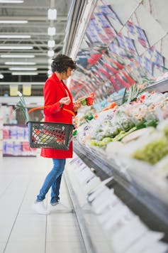Woman selecting vegetables from the fresh produce section of a supermarket