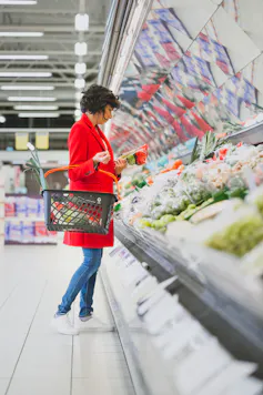 Woman selecting vegetables from the fresh produce section of a supermarket