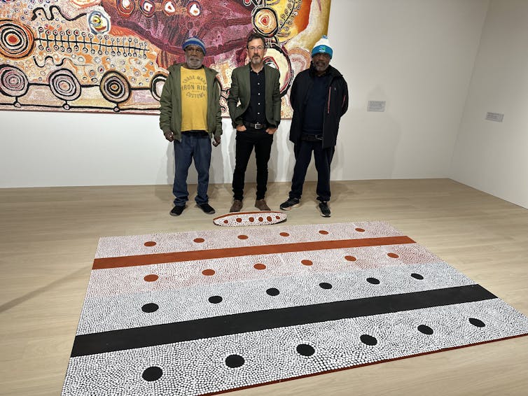 A black, white and red painting sits on the ground.