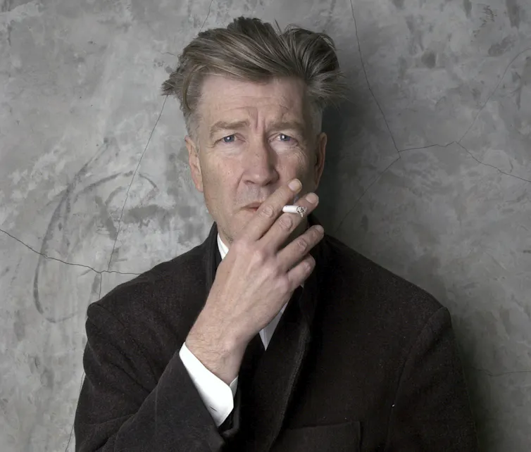 Lynch smokes a cigarette.