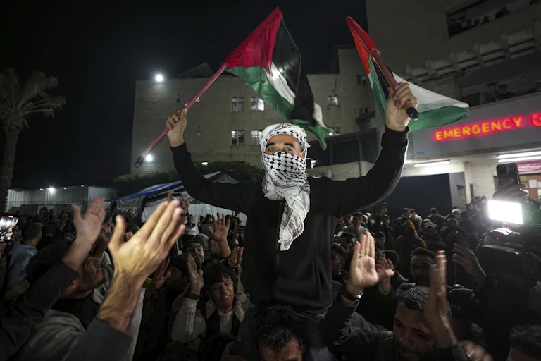 A Palestinian man celebrating and waving flags in a crowd