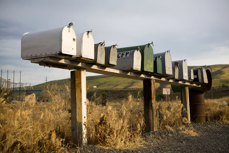 A row of rural mailboxes with fields behind them.