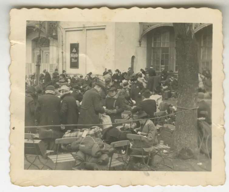 Large group of people wearing Jewish stars gather outdoors, carrying bundles of their belongings