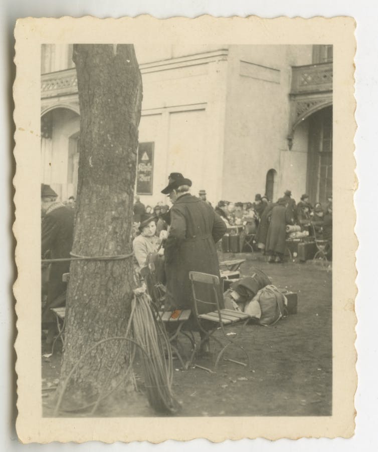 Black-and-white image of a group of people, partially blocked by a tree