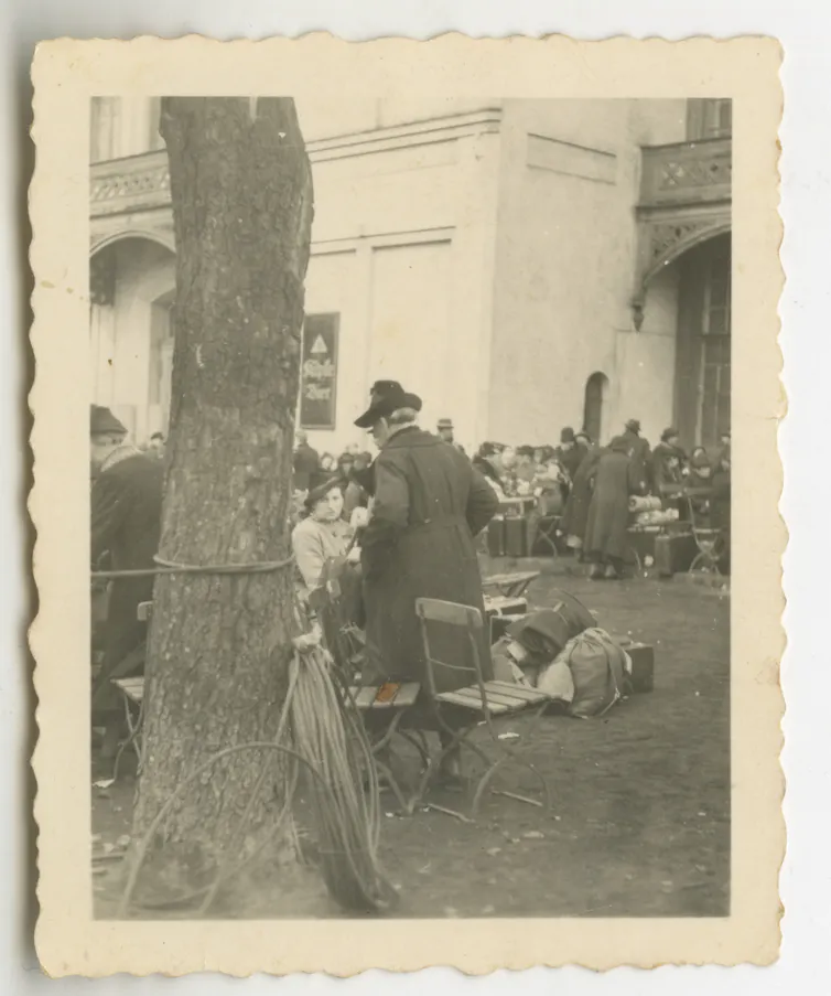 Black-and-white image of a group of people, partially blocked by a tree
