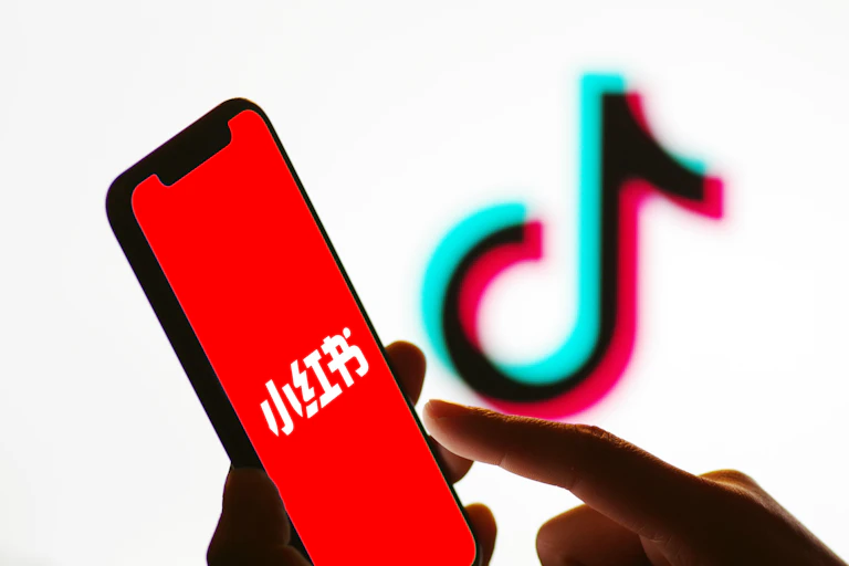 a finger points to a smart phone screen with a red background and stylized Chinese characters
