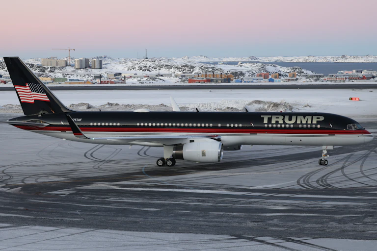 A passenger jet that says Trump on its fuselage sits on a wintry runway.