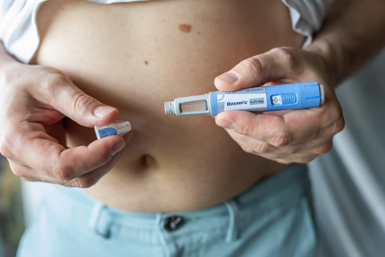 A person holds an Ozempic pen in front of their chest
