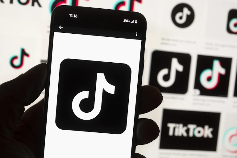 Phone screen showing TikTok logo on a backdrop with more logos.