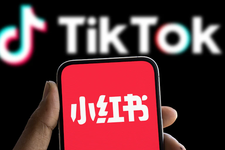 Xiaohongshu logo displayed on smartphone and tiktok logo in the background.