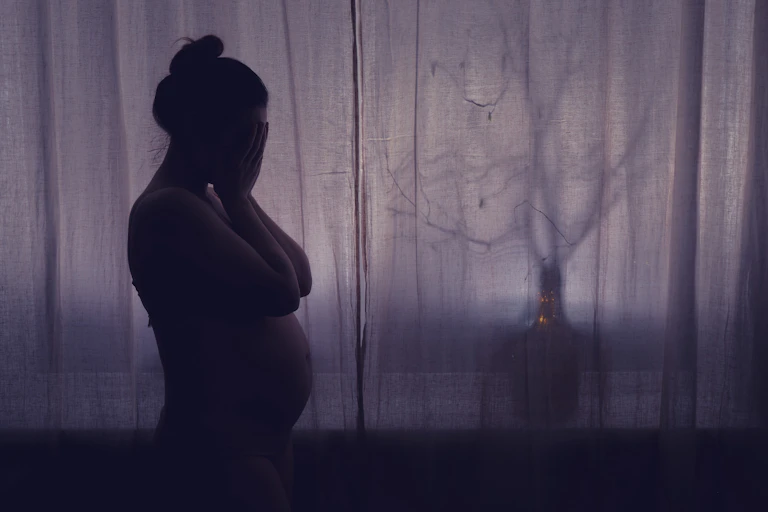 Silhouette of a pregnant woman at a window
