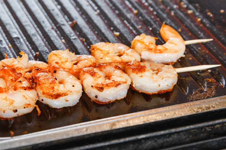 A skewer of prawns on a barbecue.