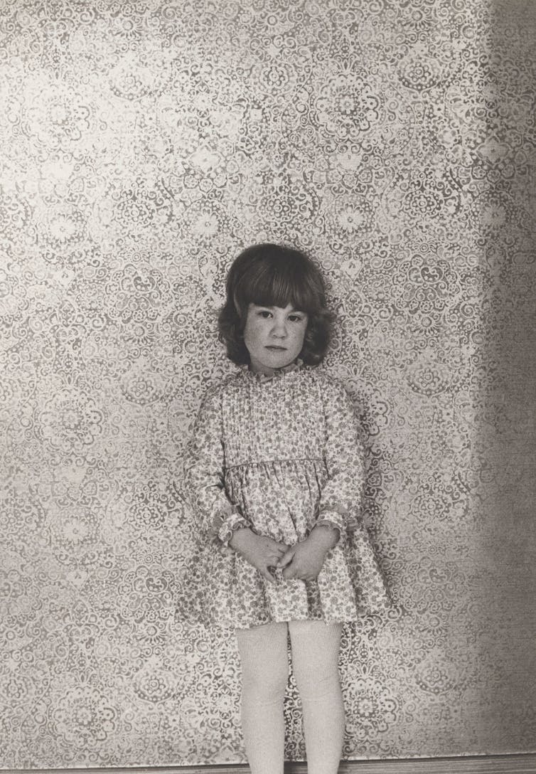 A young girl shyly poses.