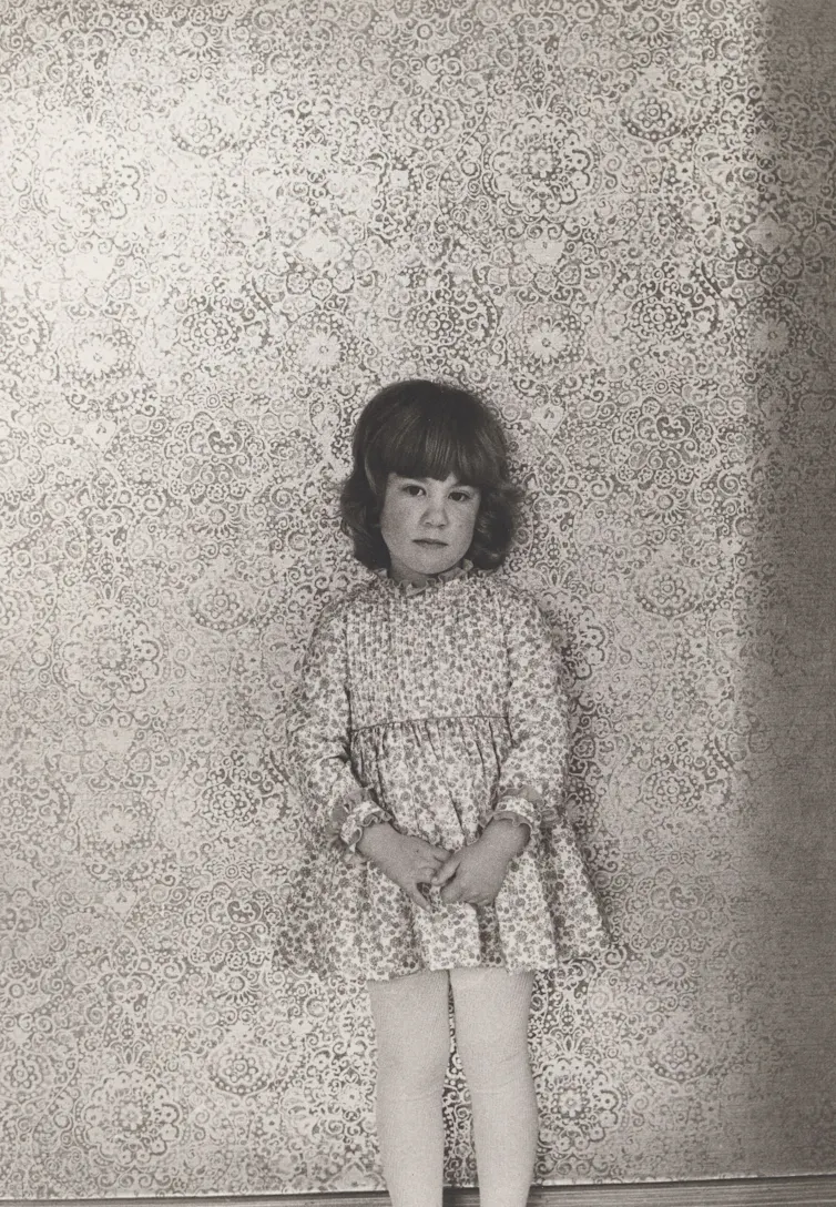 A young girl shyly poses.
