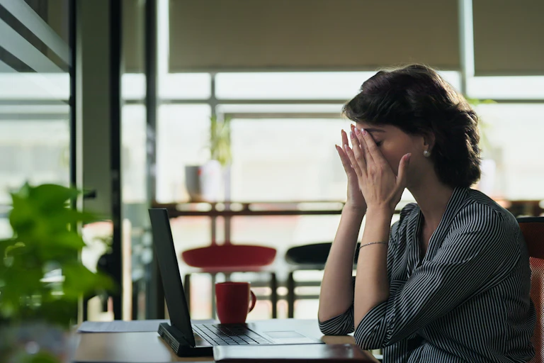 Woman sitting at desk rubbing her eyes