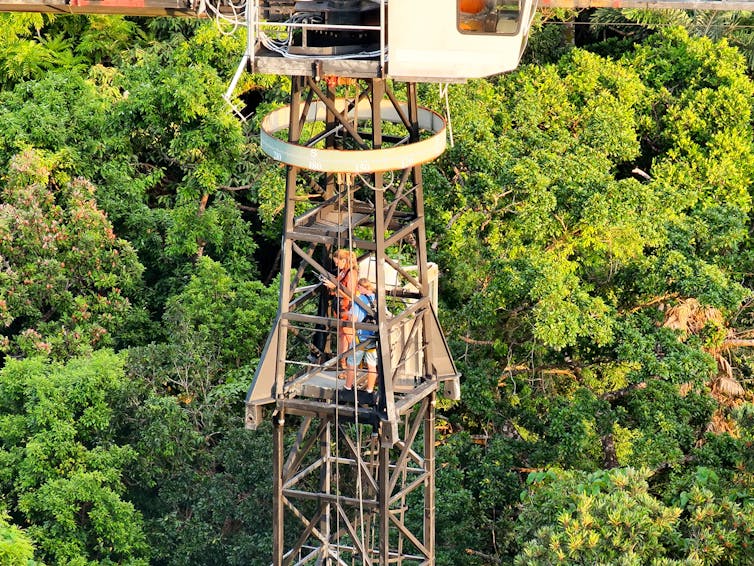 A high view of a platform where people in safety gear stand operating drones.