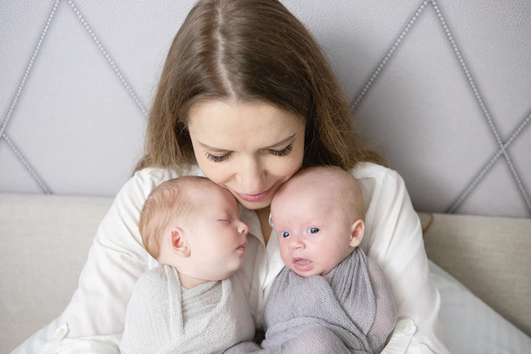 A woman holds her two infant twins.