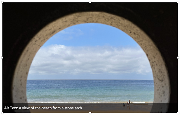 A screenshot of an image with the alt-text description that reads A view of the beach from a stone arch.
