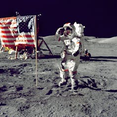 Astronaut next to American flag on the Moon.