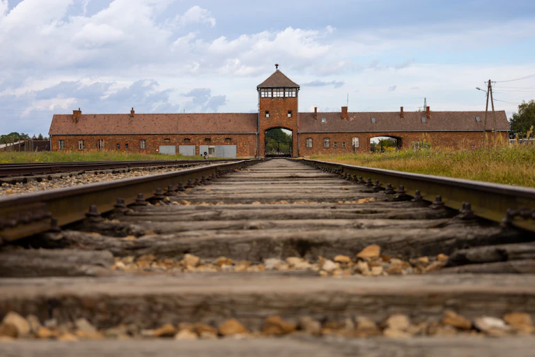 View of a disused railroad track, leading to a brick building.