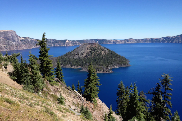 A bright blue lake surrounded by evergreen trees and rocky cliffs