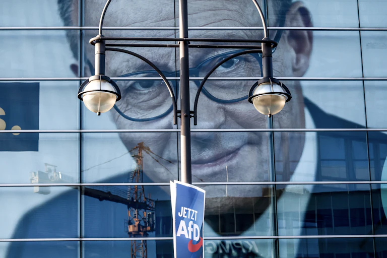 A poster of Friedrich Merz behind a small poster for the AFD.
