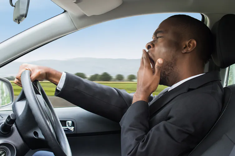 man driving while yawning