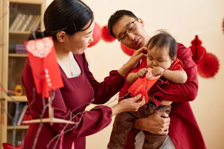 A family with a baby holding a red envelope.