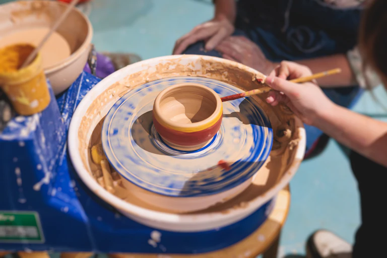 Person paints pottery on a pottery wheel