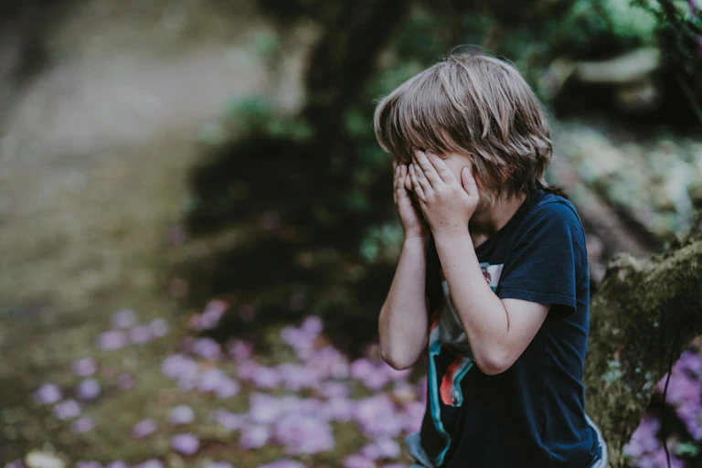 A young boy put his hands over his face.