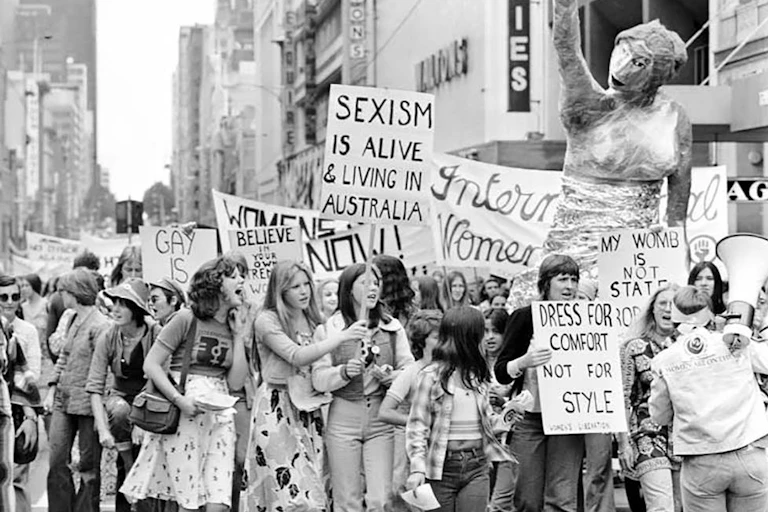 Historic black-and-white photo of women with placards marching against sexism