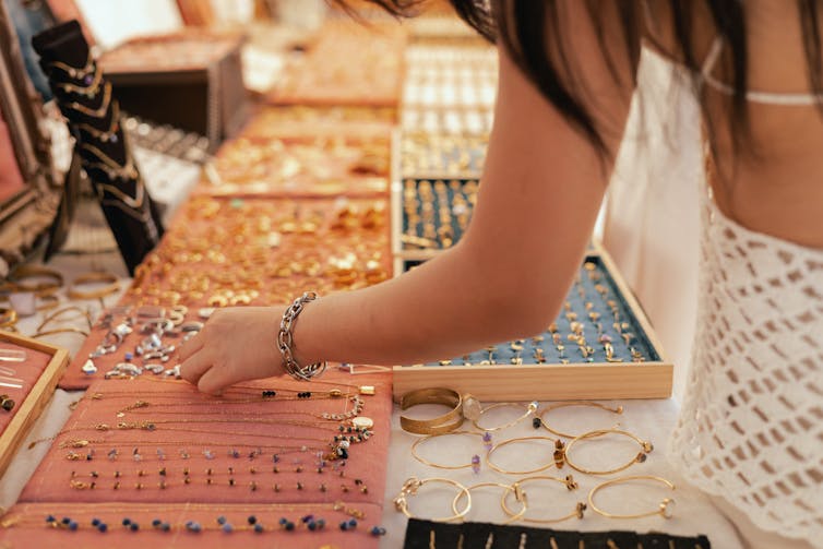 Female shopper picks out a handcrafted jewellery from a collection on a market stall