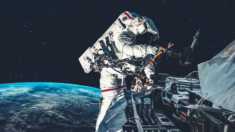 Astronaut performing spacewalk while servicing satellite