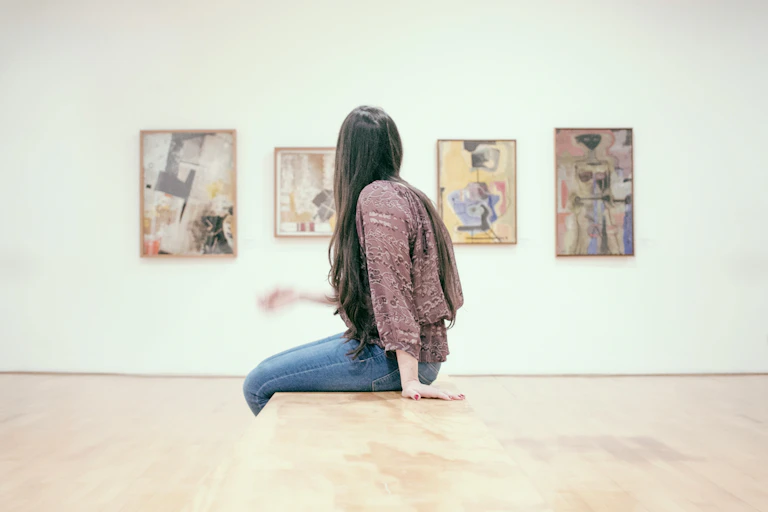A woman sits in a gallery.