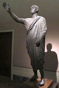 Estatua de un hombre con el brazo en alto.