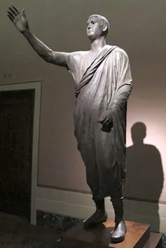 Estatua de un hombre con el brazo en alto.