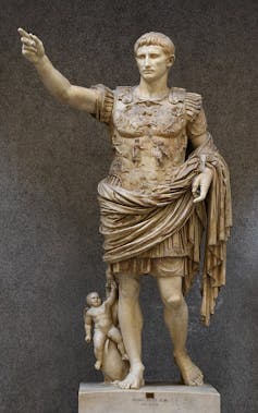 Un hombre romano vestido para la lucha alza el brazo.