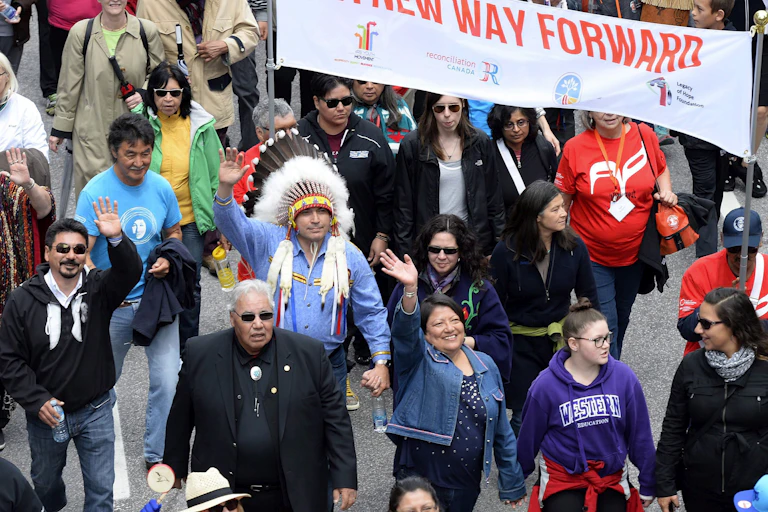 People walking in a march with banner seen, 'a new way forward.'