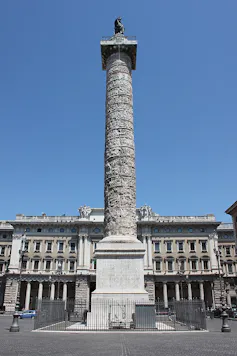 Una columna con relieves en medio de una plaza romana.