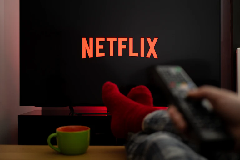 viewer pointing a remote control at at tv screen showing netflix logo