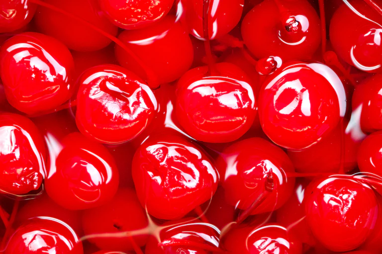Close-up of gleaming red cocktail cherries in syrup