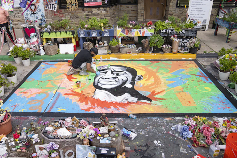 An artist working on a street mural of George Floyd