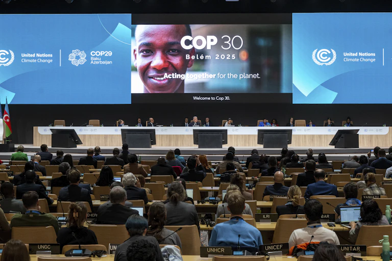 projected sign for COP30 and rows of delegates