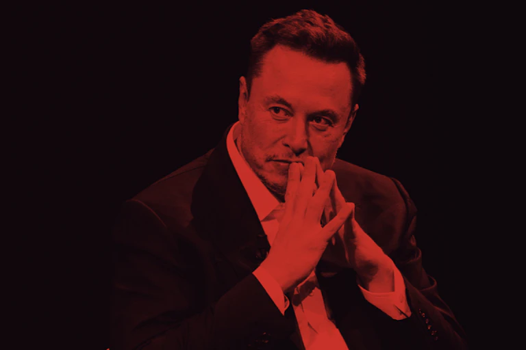 Elon Musk sits with his fingers together